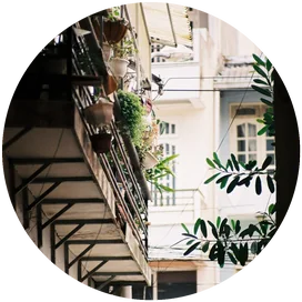 Hẻm nhỏ giữa hai dãy nhà, ban công treo đầy chậu cây và đồ đạc sinh hoạt.